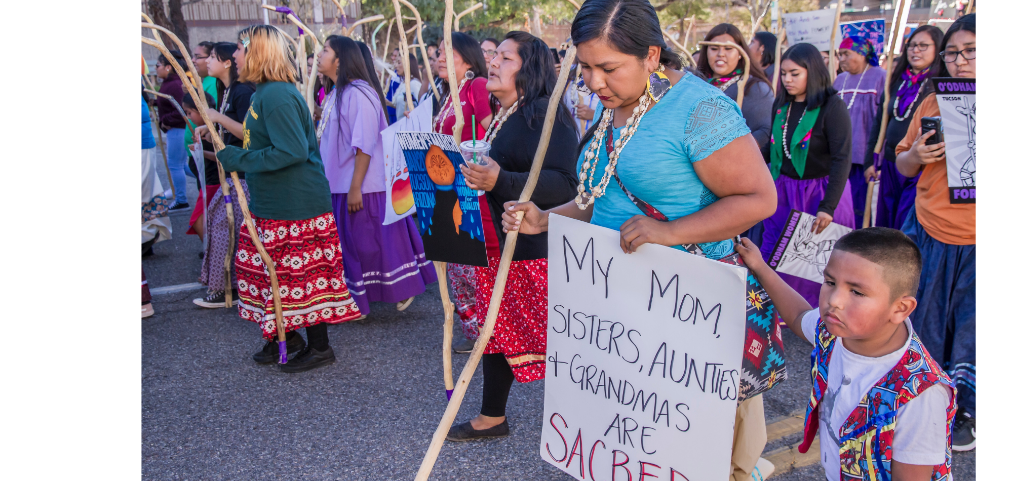 Tohono Women led the Tucson 2019 Women’s March with a show of strength, resilience and power. This woman’s sign said: My Mom, Sisters, Aunties and Grandmas are sacred. Her son was by her side. International Women’s Day