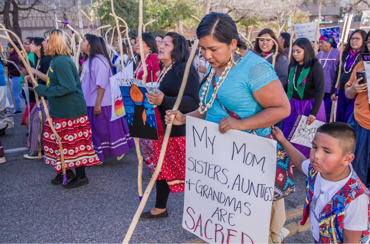 Tohono Women led the Tucson 2019 Women’s March with a show of strength, resilience and power. This woman’s sign said: My Mom, Sisters, Aunties and Grandmas are sacred. Her son was by her side. International Women’s Day