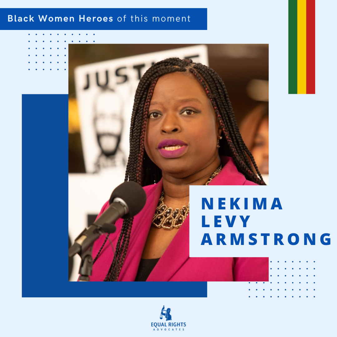photo of Nekima Levy Armstrong with labeling for Black History Month. She is mid-sentence speaking into a microphone with a serious look on her face, protester holding a sign sets the tone of the background, it reads 'justice'. She wears a maroon blazer and black top underneath with a shade of lipstick to match.