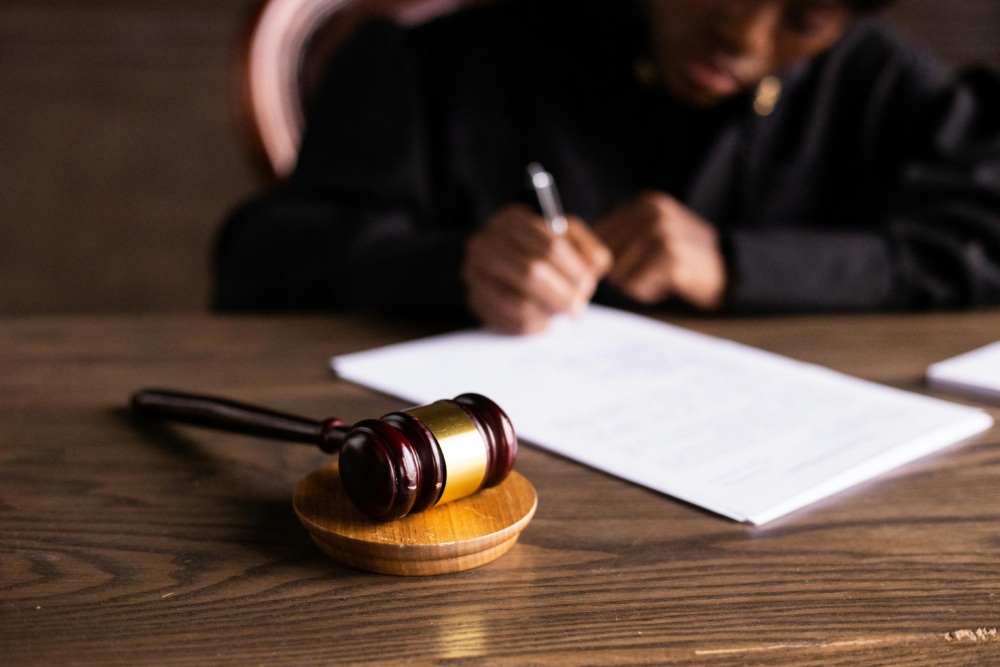 gavel on a desk with a woman blurred signing a document